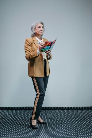 Lady wearing a blazer and black trousers with a line on the side.